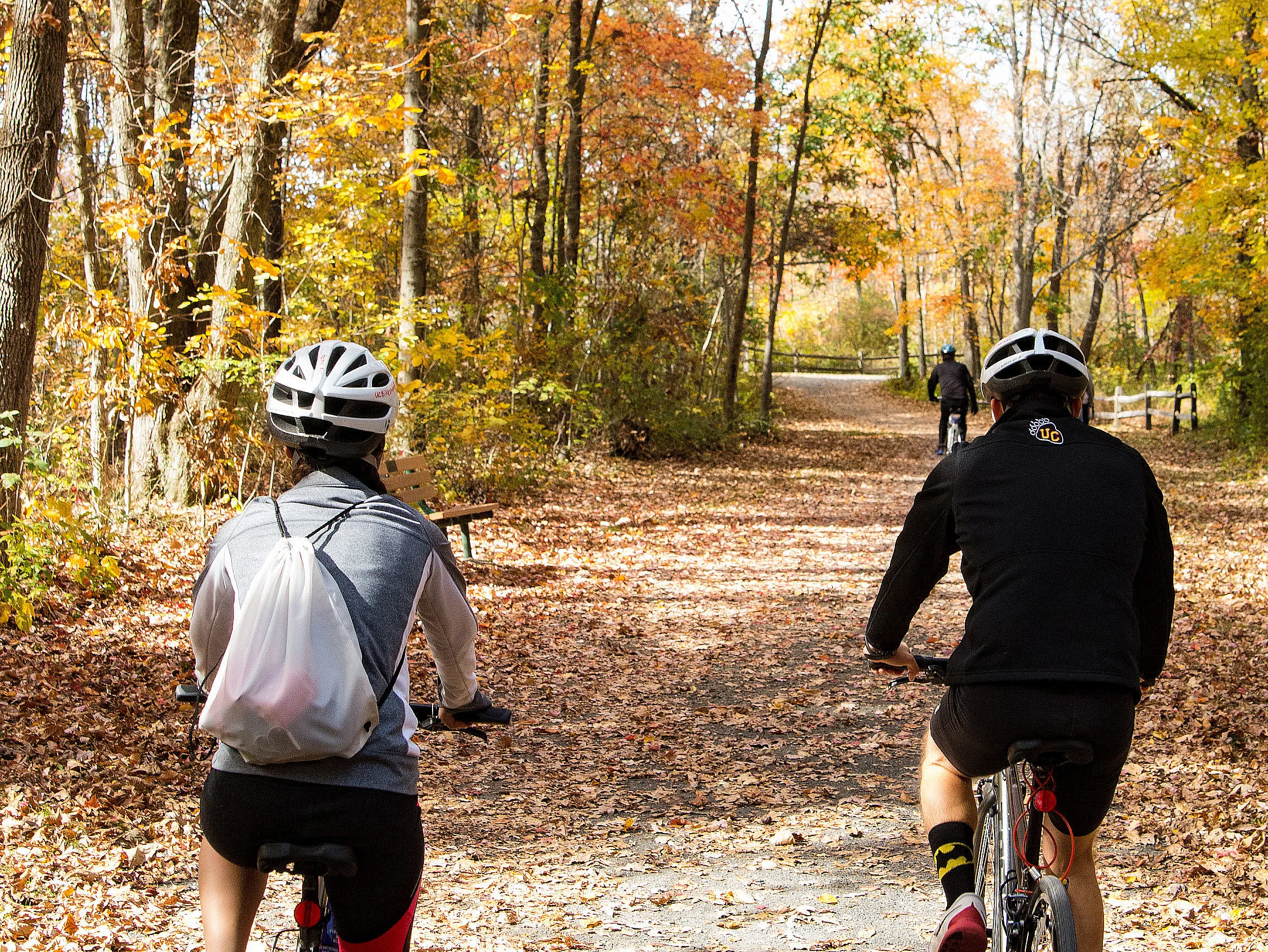 Cyclists on a leaf-covered trail through the woods near Ursinus College in autumn