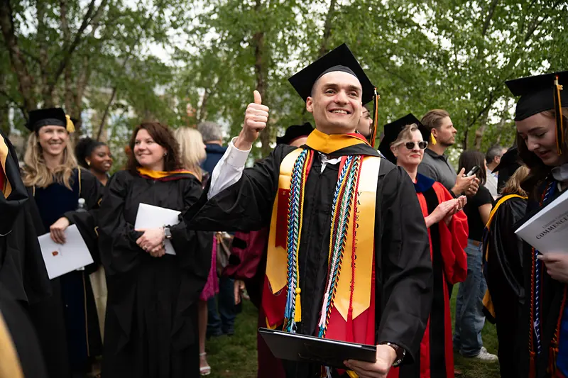 A graduate greeted on Berman Lawn after Commencement