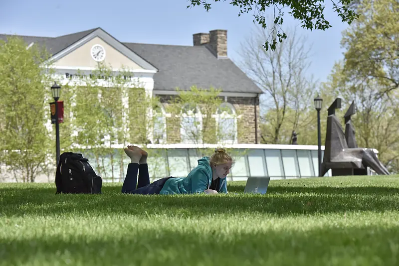A student on Berman Lawn with the Berman Museum behind