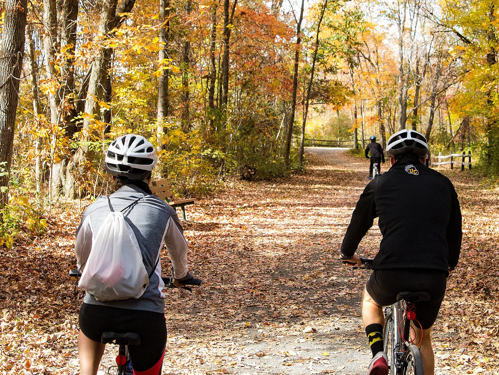 Cyclists on a leaf-covered trail through the woods near Ursinus College in autumn