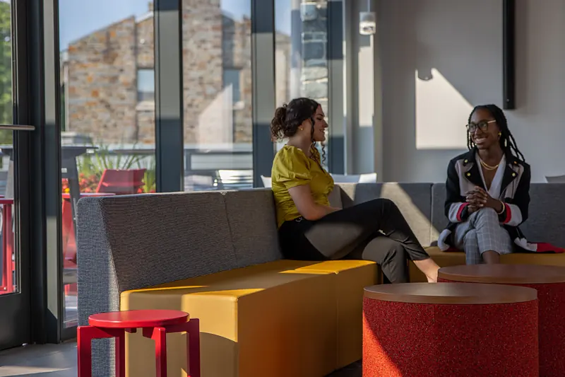 Students in conversation in a lounge inside Schellhase Commons