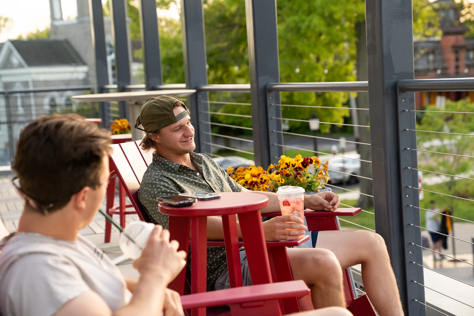 Guests on the Commons terrace among planters and red café chairs