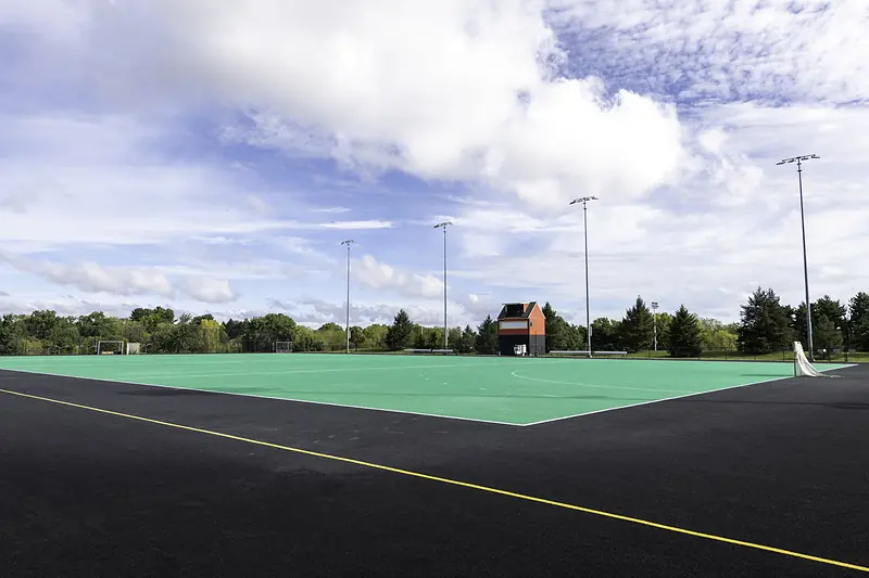 The synthetic turf of Snell Alumnae Field under tall field lights