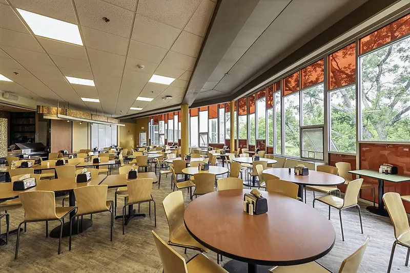 Round tables and chairs beside the tall windows of the Red Alcove in Wismer Center